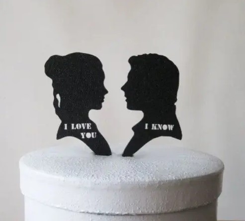 a wedding cake topped with silhouettes of Lea and Han Solo and their favorite phrases
