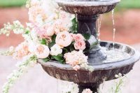 a wedding fountain with pink roses and peonies floating in it looks very chic, refined and romantic