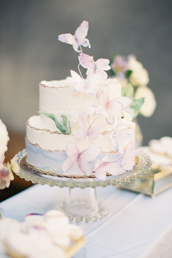 a whimsical pastel bridal shower cake with blue watercolors, with pastel butterflies and greenery is an amazing idea for a vintage bridal shower