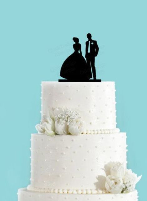 a white polka dot wedding cake decorated with white blooms and a silhouette cake topper is a stylish idea for a modern wedding