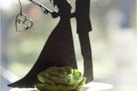 a white wedding cake topped with a succulent, a fun black silhouette is a cool and fun idea for a modern wedding