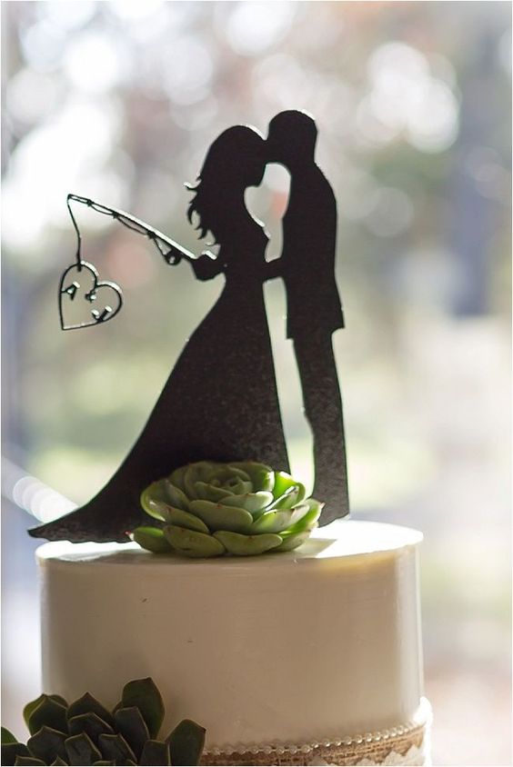 a white wedding cake topped with a succulent, a fun black silhouette is a cool and fun idea for a modern wedding