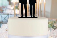 a white wedding cake with a silver ribbon and a black couple’s silhouette cake topper is a stylish and laconic idea