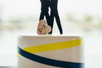 a white wedding cake with yellow and navy ribbons, a black couple silhouette cake topper, a heart is a lovely idea