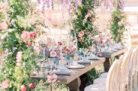an adorable floral bridal shower with an overhead installation, bright blooms and greenery, blue glasses and candles
