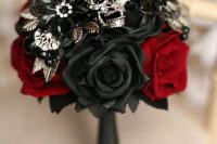 an elegant black and red silk rose wedding bouquet with vintage brooches and an embellished skull is ideal for a Halloween wedding