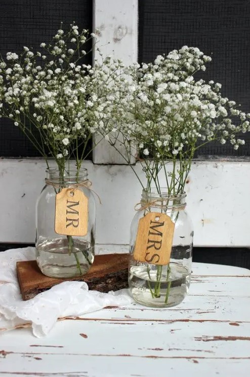 clear jars with baby's breath and tags are cool and simple barn wedding centerpieces