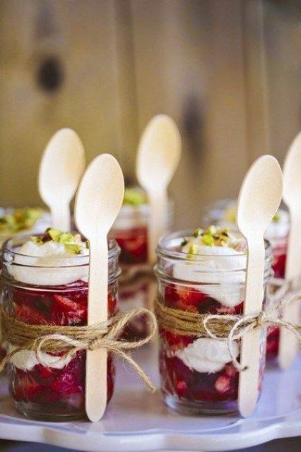 mason jars with wedding desserts and wooden spoons are a nice way to serve food at a rustic wedding