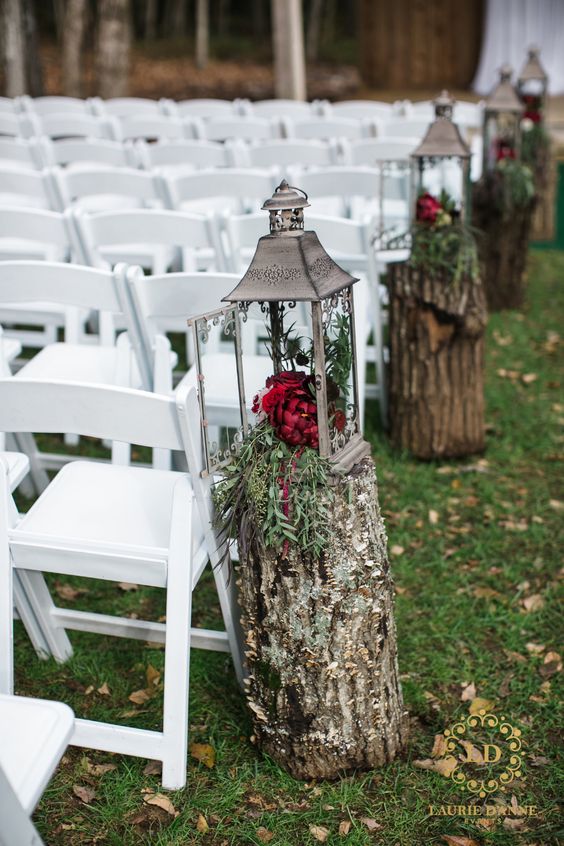 tree stumps with candle lanterns and burgundy blooms are amazing to line up a fall wedding aisle