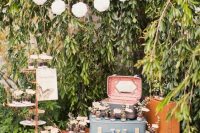 vintage bridal shower decor with lots of vintage suitcases, potted greenery, a pompom garland over the space is cool and easy to make yourself