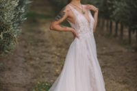 a beautiful A-line wedding gown with a lace bodice on thick straps, a plunging neckline and a layered skirt