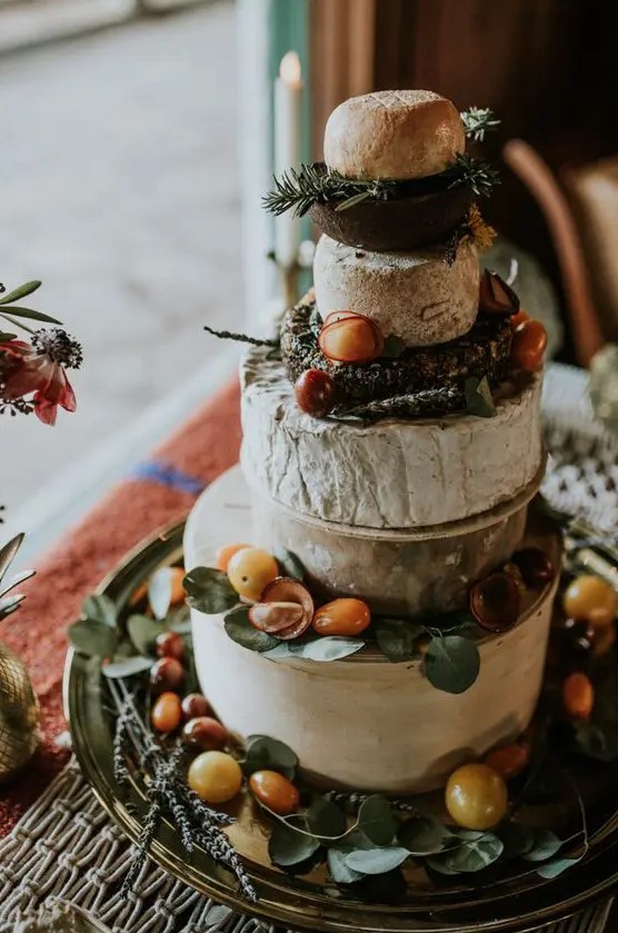a beautiful rustic cheese wheel cake tower topped with herbs and tomatoes is a lovely idea for a rustic wedding