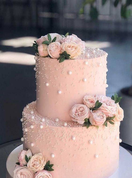 a blush wedding cake decorated with pearls and polka dots, pink blooms and greenery is a beautiful and delicate idea for a spring or summer soiree