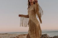 a boho lace gold sheath wedding dress with an illusion neckline and long fringe all over the dress