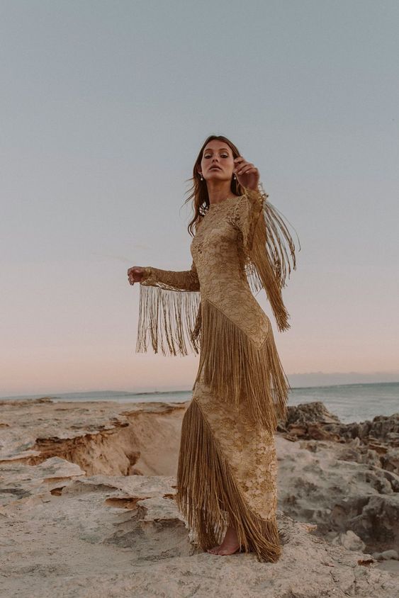 a boho lace gold sheath wedding dress with an illusion neckline and long fringe all over the dress