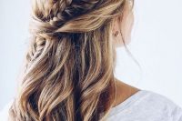 a boho wedding hairstyle with a fishtrail braid coming from the front to the back and twists plus waves down