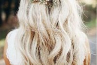 a boho wedding half updo with a volume on top, a braided part and waves down plus a pearl hairpiece and baby’s breath