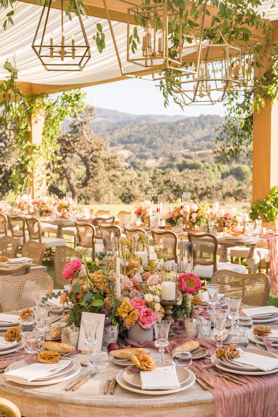 a bright fairy-tale wedding reception with bold pink and mustard blooms and greenery and candles, pink runners plus chic vintage chairs