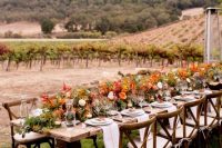 a bright harvest-inspired fall vineyard wedding reception with a vintage table and chairs outdoors, bodl blooms and berries