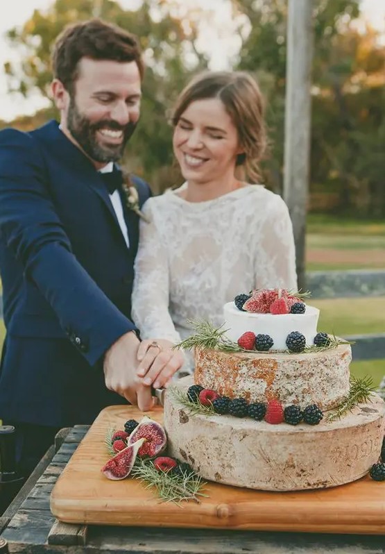 a cheese tower topped with herbs, blackberries and raspberries is a fantastic idea for a vineyard wedding with a boho feel