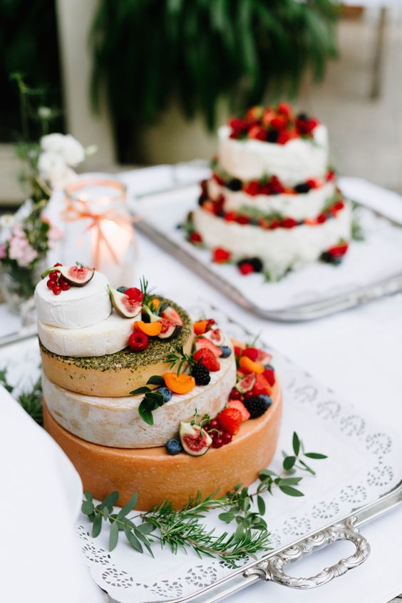 a cheese wheel tower topped with fresh fruit and berries plus herbs looks spectacular and is ideal for a vineyard wedding