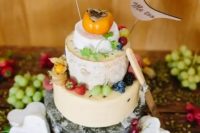 a cheese wheel wedding cake topped with fresh fruit and veggies, with plywood bird toppers with wood burning is a very cool idea
