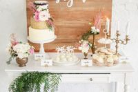 a chic and bright wedding dessert table with greenery, white and pink flowers, candles, sweets topped with blooms