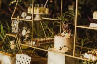 a chic dessert table of gold metal constructions with glass shelves and neutral blooms and greenery
