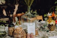a chic tropical wedding tablescape with neutral linens, orange blooms and yellow ones, tropical elaves and tiny pineapples