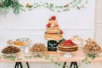 a colorful summer wedding dessert table with greenery garlands, red flowers and sweets topped with blooms