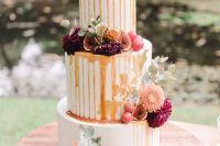 a delicious-looking fall wedding cake with fresh figs and grapes, with burgundy and orange dahlias and caramel drip is a fantastic idea for a fall vineyard wedding