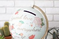 a globe with painted words and images and a gilded touches is a very cool wedding card box for a couple inspired by travelling