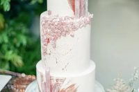 a large white wedding cake decorated with edible rose quartz and rose gold splashes is very refined and chic