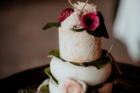 a lovely cheese stack wedding cake with foliage, blush and bold pink blooms plus a yarn heart topper is amazing for your wedding