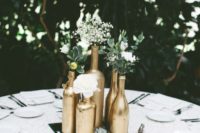 a mirror tray with gold bottles, white blooms, greenery and a succulent is a nice centerpiece for many weddings