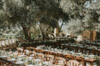 a modern rustic vineyard wedding reception with stained furniture, greenery runners and white porcelain is a chic space