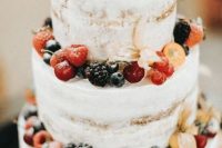 a naked wedding cak completely covered and topped with lots of fresh berries is a great idea for a vineyard or boho wedding in summer