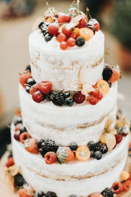 a naked wedding cak completely covered and topped with lots of fresh berries is a great idea for a vineyard or boho wedding in summer