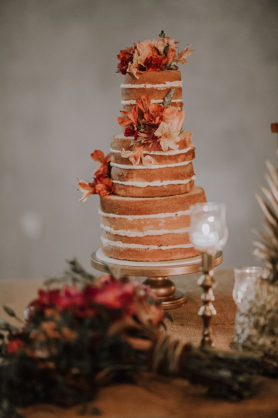 a naked wedding cake decorated with orange and blush blooms is a gorgeous idea for an orange boho wedding