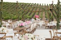 a neutral vineyard wedding reception space with neutral linens, neutral and pink blooms and pillar candles