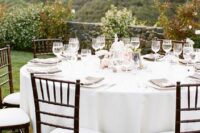 a neutral vineyard wedding reception with linens, grey menus and white chairs and a lovely vineyard view