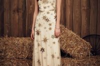 a neutral wedding dress with embellished and shiny gold stars, no sleeves and an illusion neckline for a celestial bride