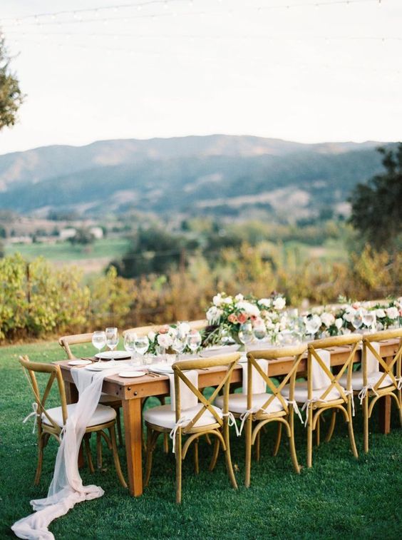 a neutral wedding reception with airy white runners, neutral and bold blooms and greenery and white chairs