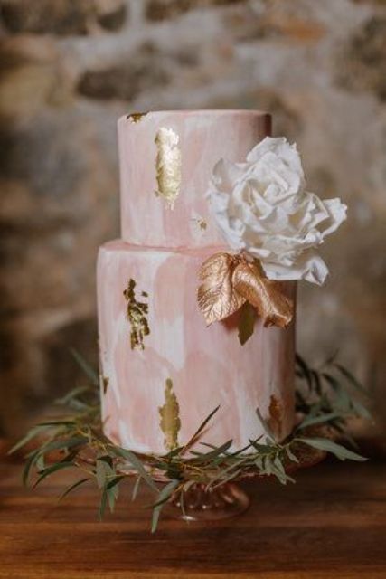 a pink and white marble wedding cake with a white sugar bloom and gold leaves plus gold foil is a stylish idea to rock