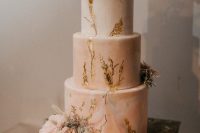 a pink marble wedding cake with gold leaf, frehs blush blooms and greenery and a calligraphy topper looks refined and very romantic at the same time