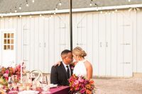 a refined and bold vineyard fall wedding reception with much purple, bold and lush florals and greenery, elegant candles