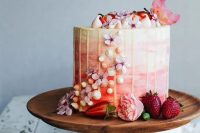 a romantic ombre pink wedding cake with creamy drip, meringues, pink blooms and petals is beautiful