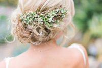 a romantic wavy side updo with a volume on top and a fresh flower and greenery hairpiece for a natural feel