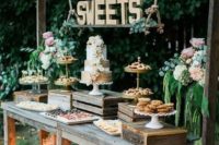 a rustic dessert table made of weathered wood, with crates and boxes, with wooden letters on ropes and lots of candles