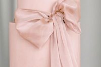 a sleek blush wedding cake with a pink ribbon bow is a stylish and trendy idea as huge bows are a trend of 2022